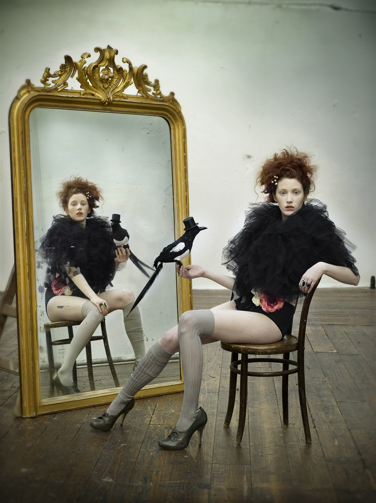 fashion editorial studio shoot of a redhead female , model in front of the mirror with vintagge props wearing contemporary irish design
